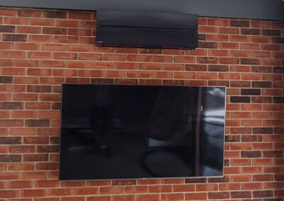 Jednostka klimatyzatora wewnętrzna wisząca na ścianie nad telewizorem